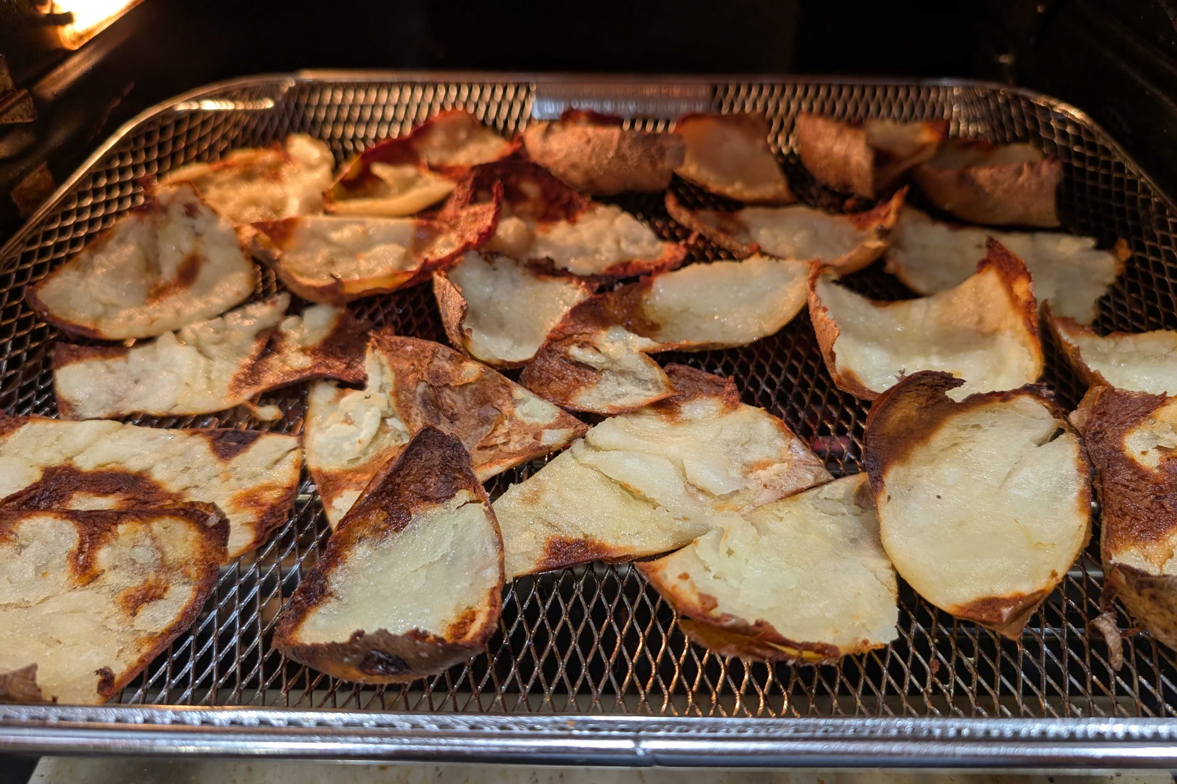 Crispy potato skin chips in a bowl, golden brown with blistered edges, seasoned with salt